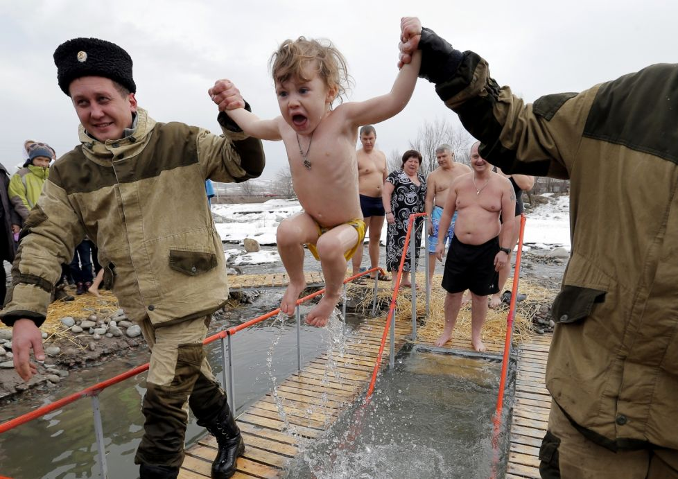 Lumea în imagini, fotografiile zilei de 21 ianuarie . Un copil a fost scăldat într-un lac înghețat, de sărbătoarea Bobotezei pe ritm vechi